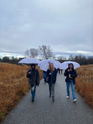 A group of students strolling along a path with umbrellas