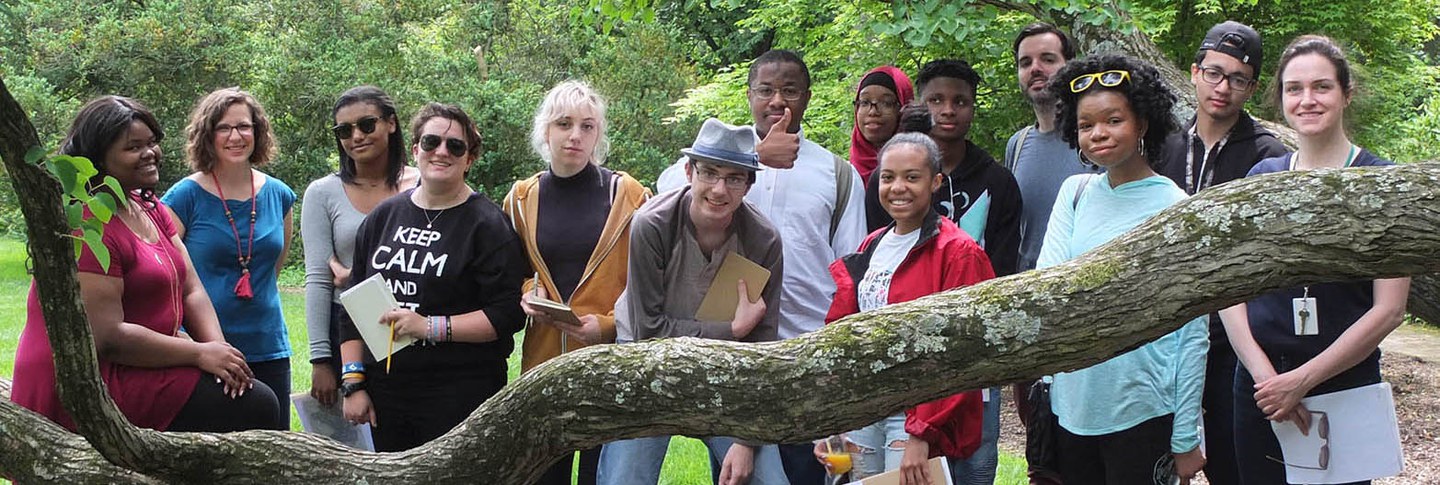 A diverse group of high-school students posing outdoors with tree branches.