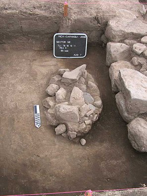 Fig. 5: The western, north–south trending Inca wall (Fea 2), also on north side of semi-subterranean temple, on right side of photo, with shallow rock-covered pit burial (Fea 3) located to east of wall in center of photo. Rock debris used to cap burial included numerous fragments of broken manos and metates.