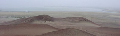 View from the top of Cerro Colorado, over the twin knobs of the Wari Kayan hillside. The Necropolis funerary bundles, massed on that hillside, faced to the north towards this view of the bay of Paracas.