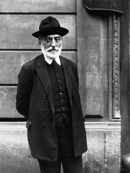 Photograph of Miguel de Unamuno standing in front of a stone wall