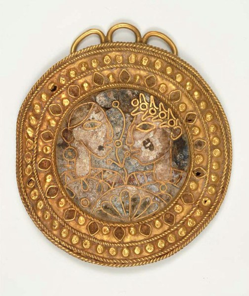 Round pendant or brooch with two heads facing each other outlined in gold