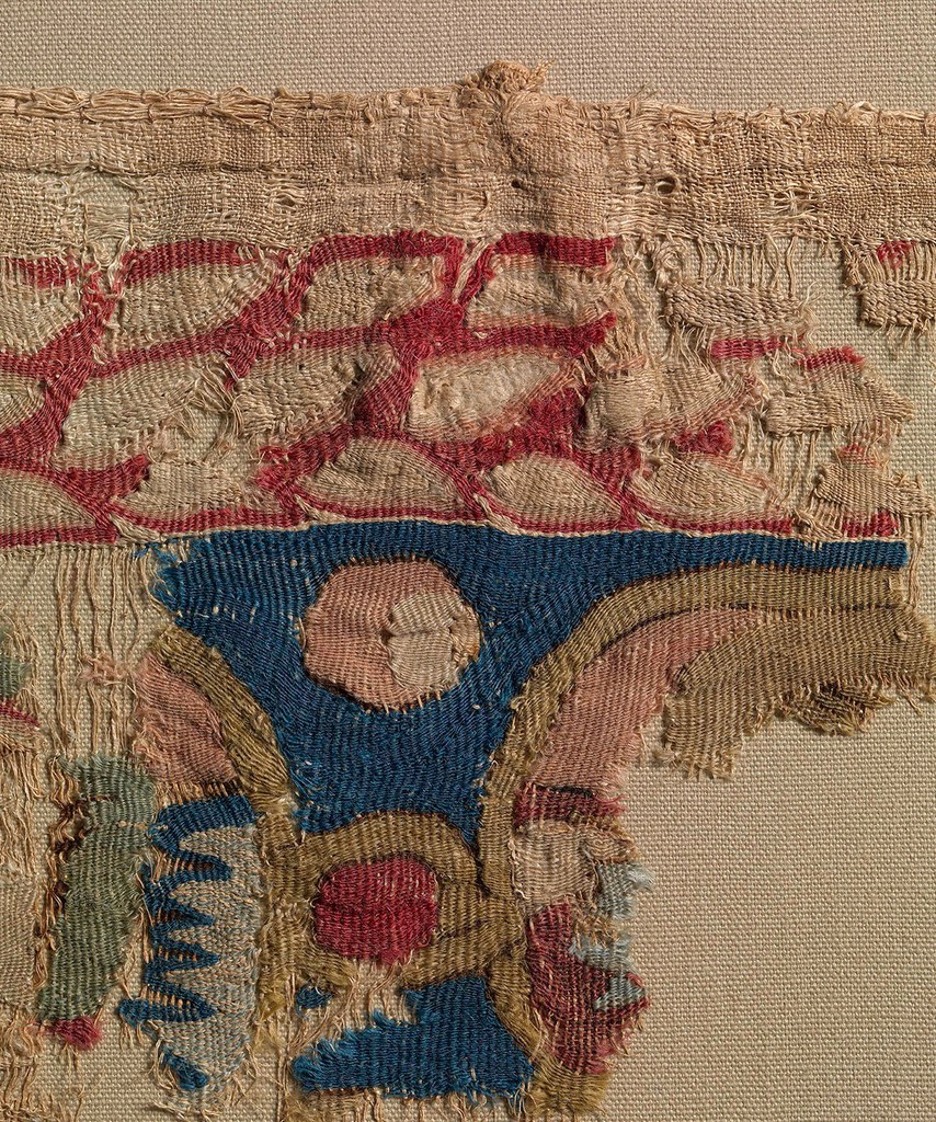 Detail of the upper-right corner of the fragment of Hanging with Riders, showing narrow strips of linen cloth sewn at an angle to the reverse of the hanging