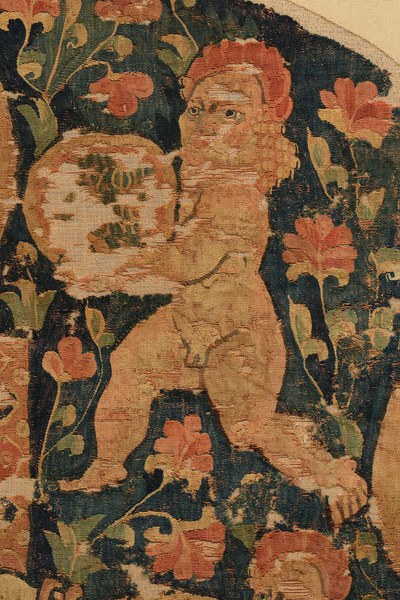 Detail of Hanging with Hestia Polyolbos (fig. 1), showing flowers in the background and the genius on the upper right