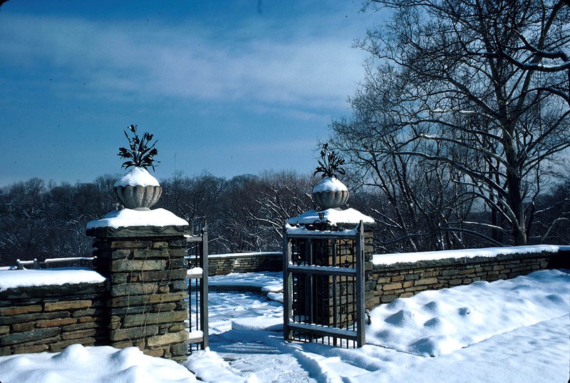 Iron bouquets atop stone pillars with Arbor Terrace covered by snow
