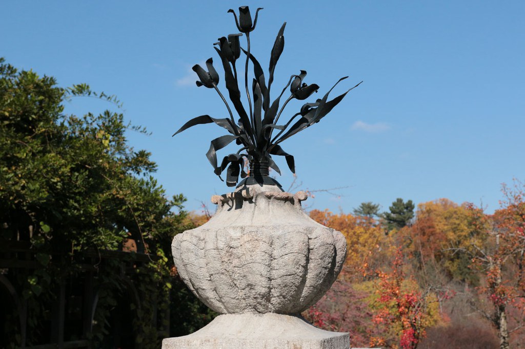 Stone vase with iron flowers atop a column